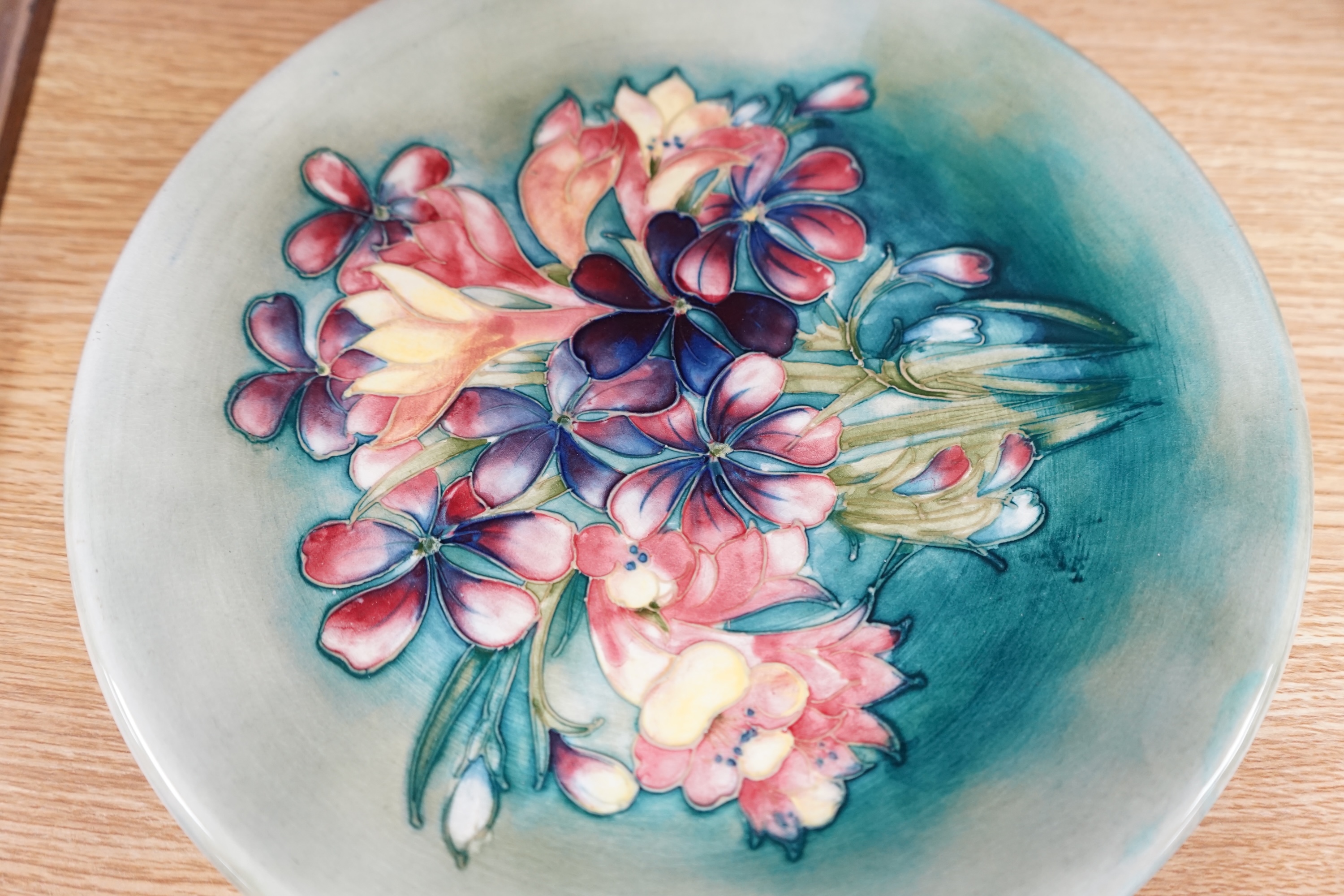 A Moorcroft spring flower pattern plate, signed to base, 26cm in diameter. Condition - good